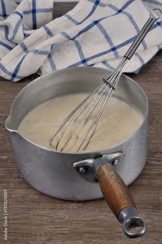 Fotografía Casserole de sauce béchamel avec un fouet de cuisine et un torchon