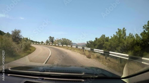 Vehicle point-of-view driving on coastal serpantin crimean road. Blue sea, green grass and trees, rocks, cliffs, mountains. photo