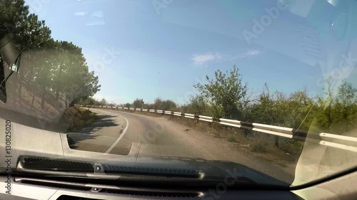 Vehicle point-of-view driving on coastal serpantin crimean road. Blue sea, green grass and trees, rocks, cliffs, mountains. photo