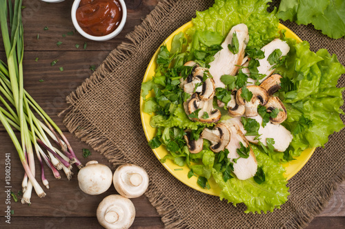 Green salad with mushrooms and chicken. Wooden background. Top view