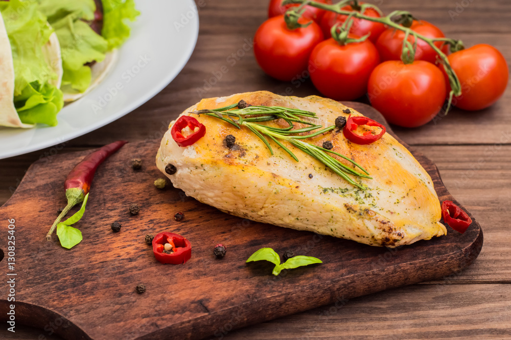 Chicken fillet, fried on the grill and laid out a wooden board with spices herbs. table. Top view Chicken fillet, fried on the grill and laid out a wooden board with spices herbs. table. Top view