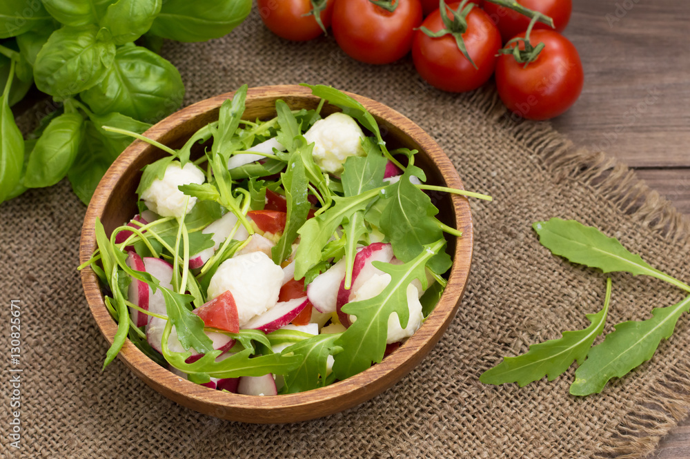 Salad with radish and arugula on a wooden background. Top view. Close-up