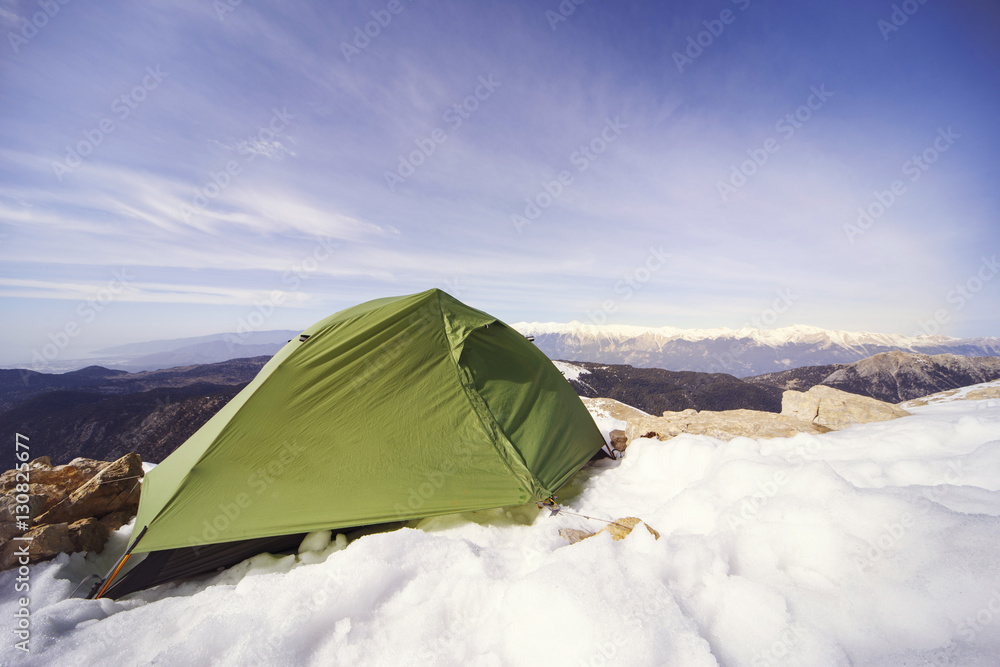Winter camping in the mountains with a backpack and tent.