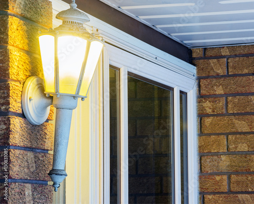 Elegant ornate porch light glowing by front door, welcoming