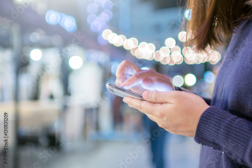 Woman touching smartphone with circle bokeh light at night live