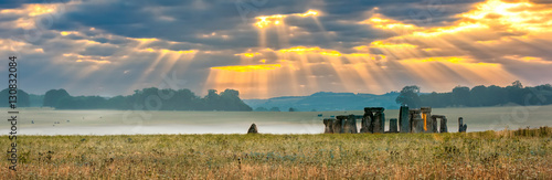Fotografia Amesbury, Wiltshire, United Kingdom - August 14, 2016: Cloudy sunrise over Stonehenge - prehistoric megalith monument arranged in circle