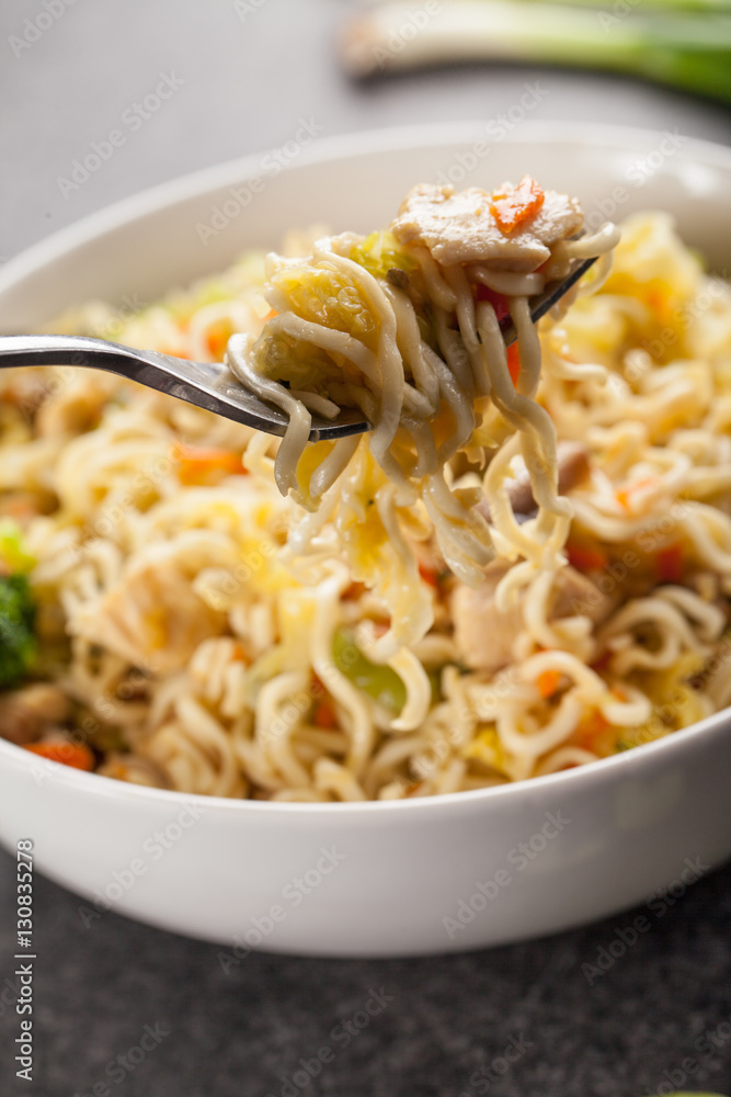 Chinese chicken lo mein with cabbage, carrots, celery, mushrooms, turnips, broccoli, and assorted vegetables with a fork ready to take a bite Chinese chicken lo mein with cabbage, carrots, celery, mushrooms, turnips, broccoli, and assorted vegetables with a fork ready to take a bite