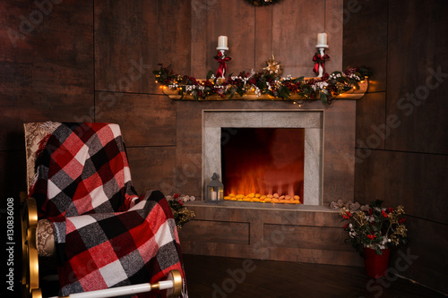 Obraz na płótnie Rocking chair in the living room with decorated flaming fireplac w salonie