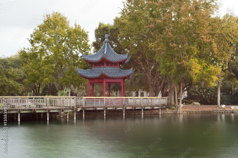 Japanese pavilion over lake with trees 