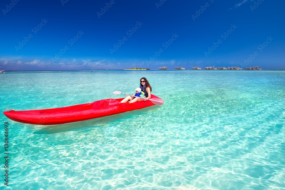 Young caucasian attractive woman with her little son kayaking on tropical island