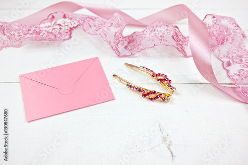 Golden hairpins with pink gemstone and pink lace on white wood