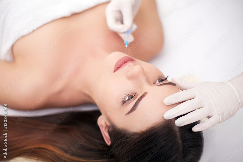Attractive woman at plastic surgery with syringe in her face