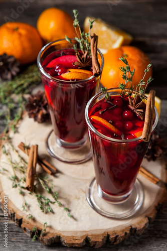 Two glasses of hot mulled wine on a dark background. Spices, oranges and fir cones