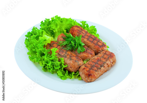Meat cutlets fried on the grill lay on the leaves of lettuce on a white plate. Fatty foods fast food.