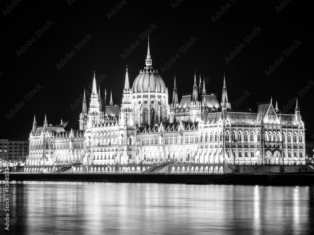 Naklejka premium Night view of illuminated historical building of Hungarian Parliament, aka Orszaghaz, with typical symmetrical architecture and central dome on Danube River embankment in Budapest, Hungary, Europe. It
