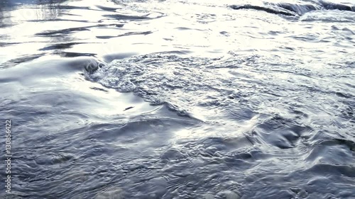 Flowing water in a blue river in slow motion