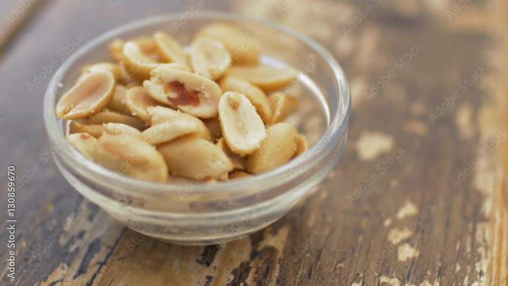Close up view of roasted salted peanuts in the glass bowl on the wooden brown old table, Valencia, Spain Close up view of roasted salted peanuts in the glass bowl on the wooden brown old table, Valencia, Spain