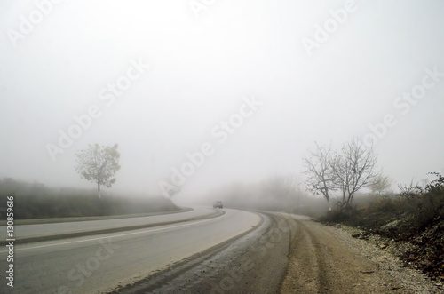 Landscape of foggy asphalt road among naked dark trees, or fog on road to mountains in winter time, Azerbaijan İsmailli