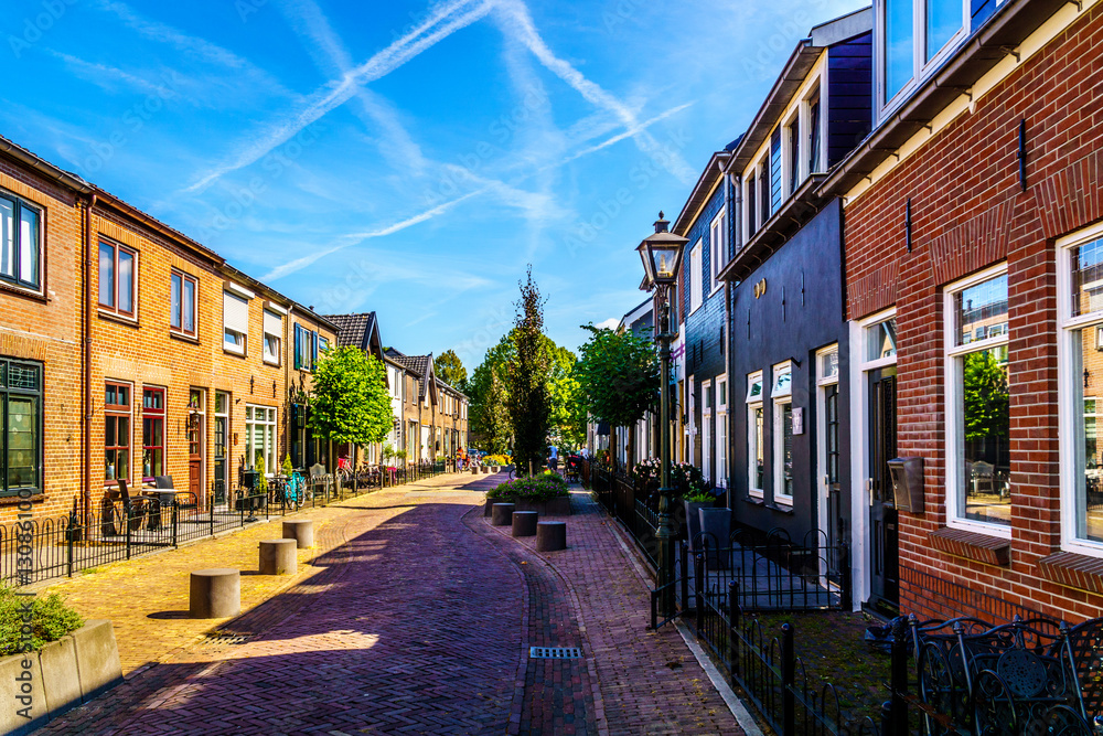 Quiet street in the historic Dutch Fishing Village of Bunschoten-Spakenburg with Renovated Row Houses on a Sunny Summer day 