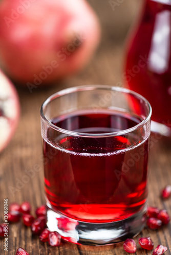 Portion of Pomegranate juice on wooden background (selective foc