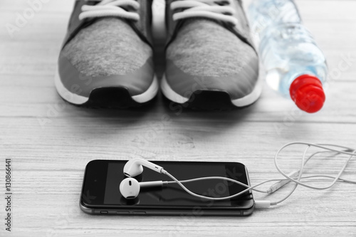 Sport shoes and cellphone on wooden background