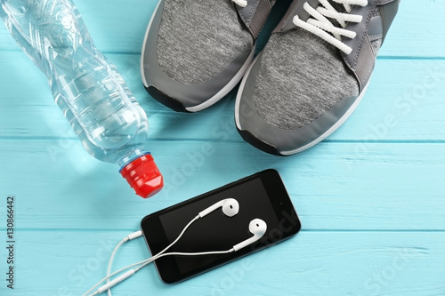 Sport shoes and cellphone on wooden background