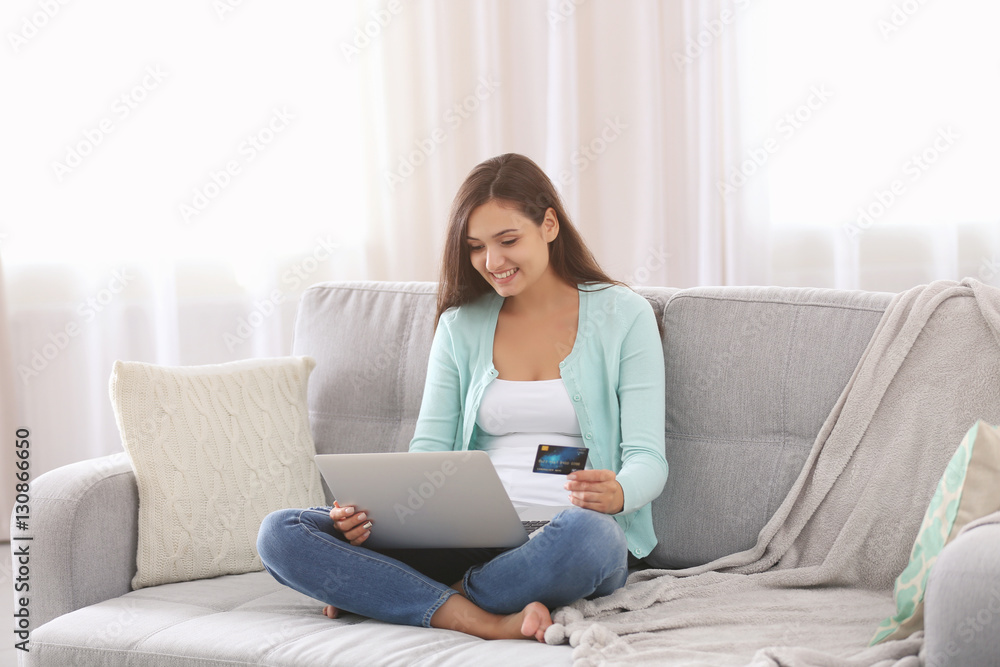 Young woman sitting on sofa and making online shopping Young woman sitting on sofa and making online shopping