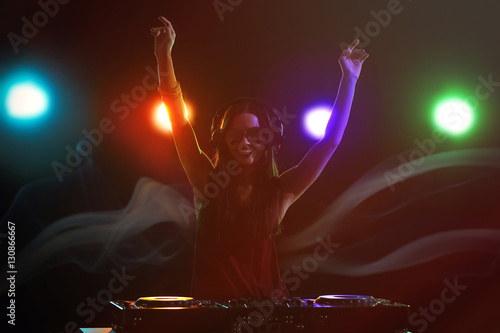 Pretty young DJ playing music in nightclub