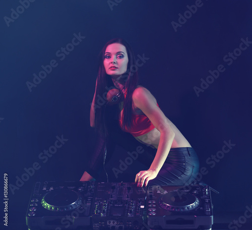 Pretty young woman with DJ console on dark background