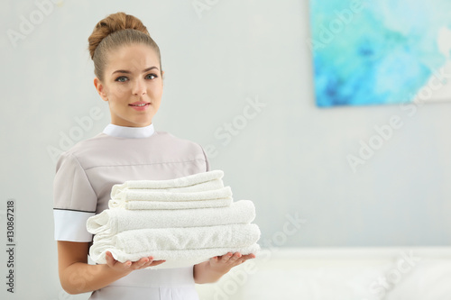 Chambermaid holding pile of...