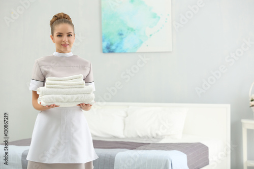 Chambermaid holding pile of...