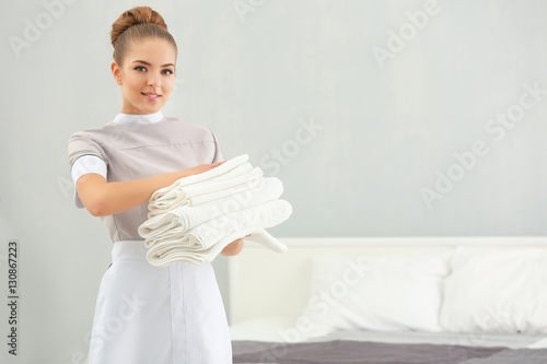 Chambermaid holding pile of...