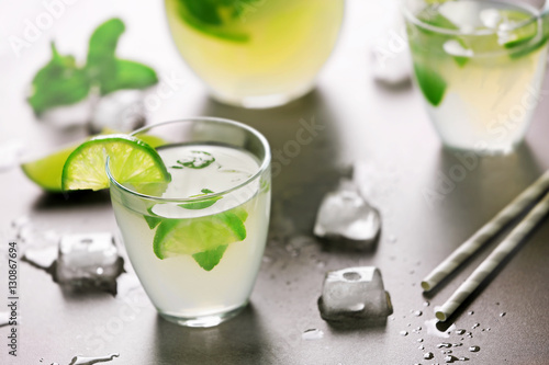 Fresh lime cocktail with ice cubes on grey background
