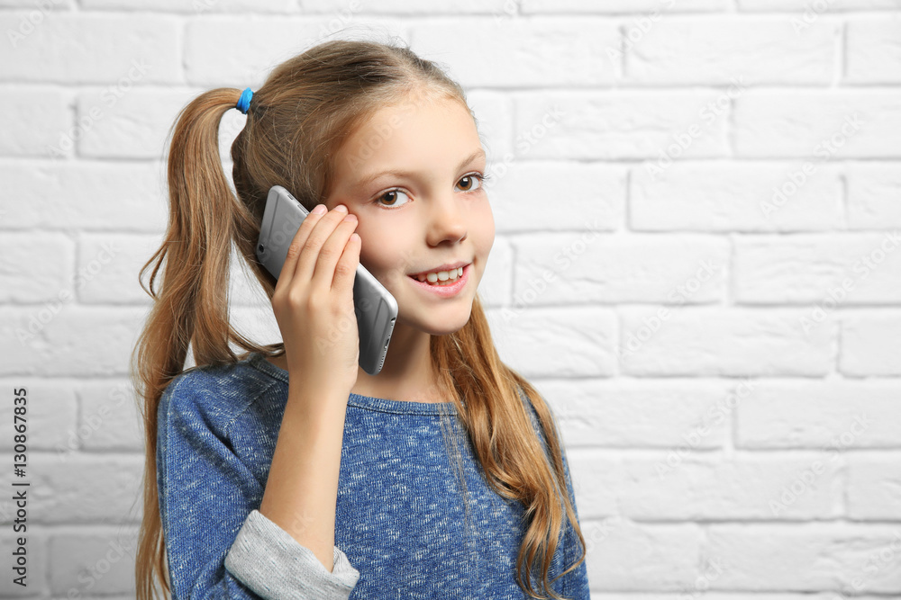 Cute girl talking by mobile phone near brick wall Cute girl talking by mobile phone near brick wall
