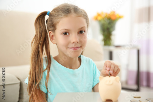 Cute girl putting coins int...