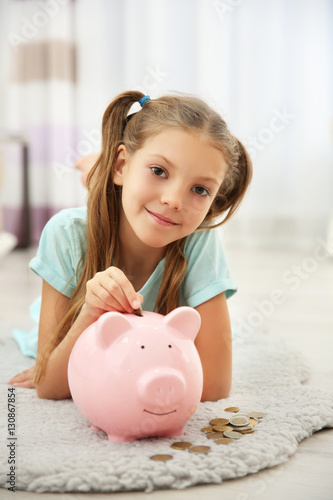Cute girl putting coins int...