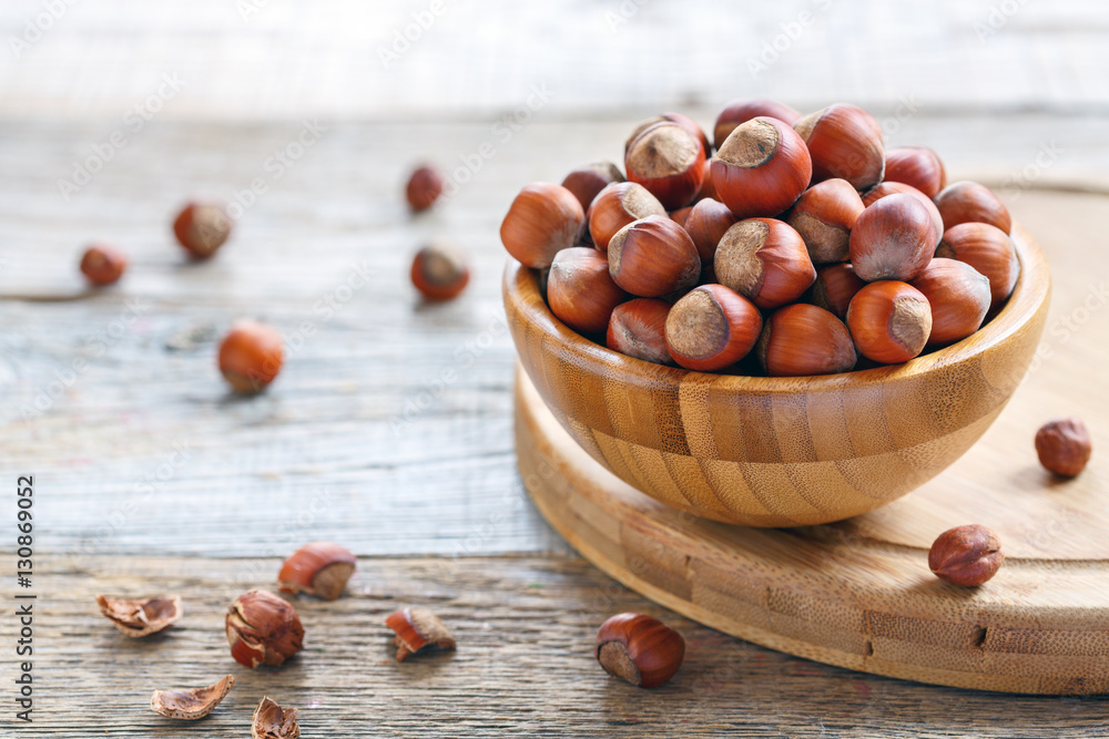 Bowl with brown hazelnuts on a stand. Bowl with brown hazelnuts on a stand.