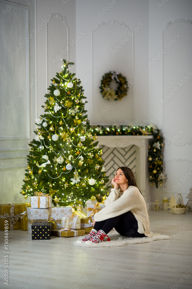Nice girl the brunette sits about the Christmas tree.