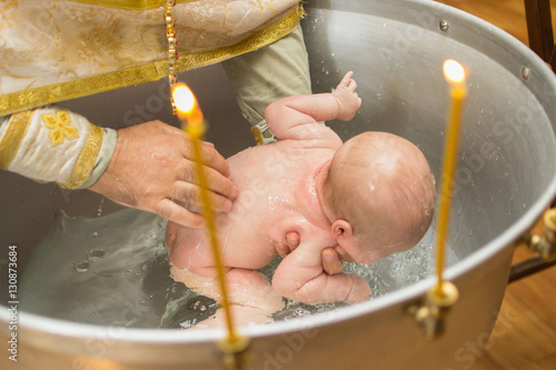Fototapeta Baby held in hand while baptizing