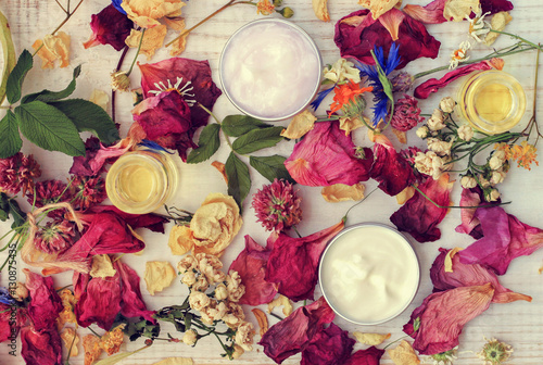 Aromatic botanical cosmetics. Dried flowers mixture, facial mask in sample jars, oils. Holistic herbal DIY skincare beauty hack. Retro pink toned.