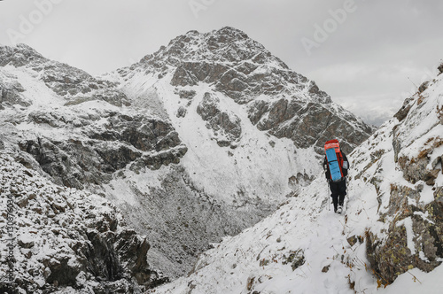Climber walking on a steep snow-covered slope in the mountains on the background of a cliff and the abyss. The concept of risk and adventure outdoor