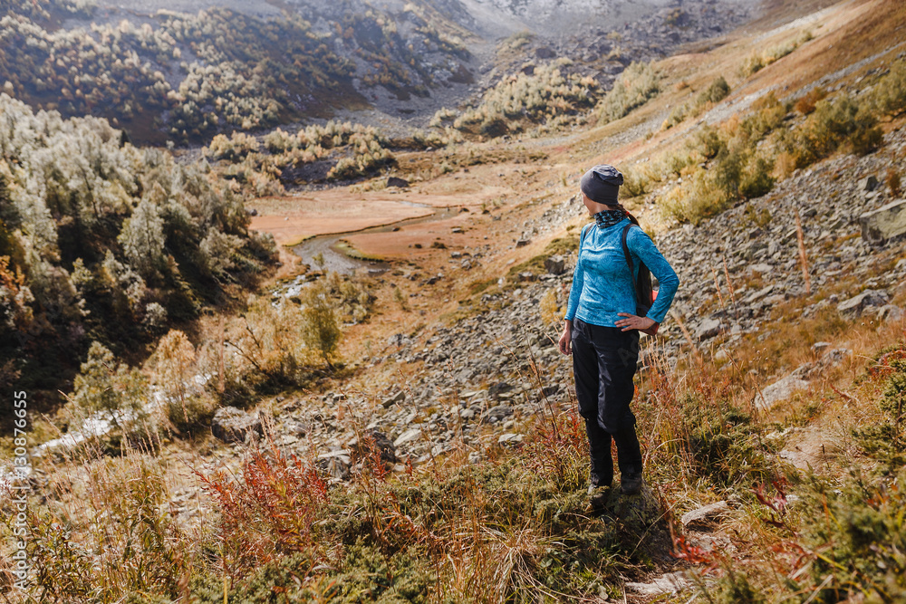 Hiker with backpack enjoying landscape of autumn mountains, rear view