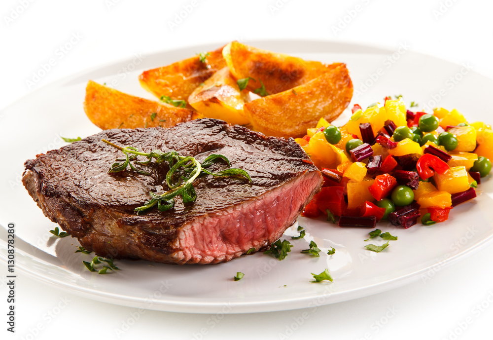 Grilled steak, baked potatoes and vegetable salad on white background Grilled steak, baked potatoes and vegetable salad on white background