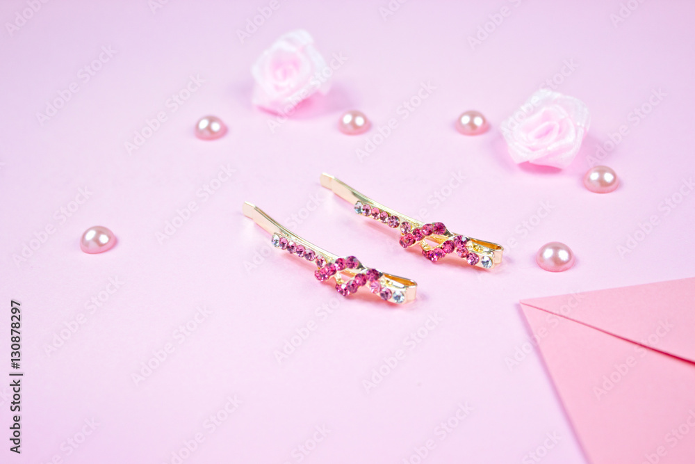 Golden hairpins with pink gemstone and pink ribbon on pink background Golden hairpins with pink gemstone and pink ribbon on pink background