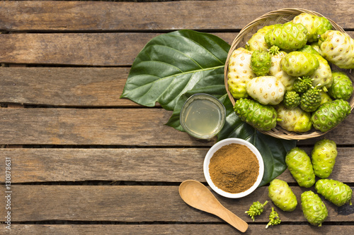Canvas Print Noni fruit and noni in the basket with noni juice and noni powder on wooden table