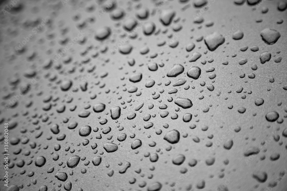 Rain drops on black and white metal surface.