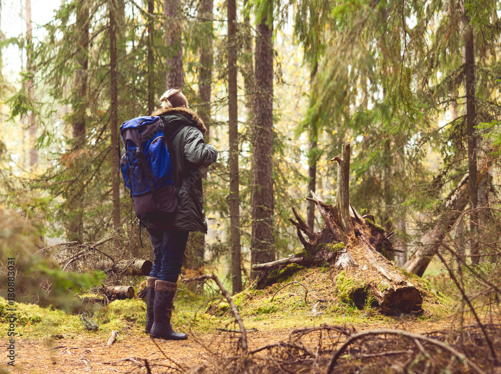 Naklejka premium Young man with a backpack hiking in a forest
