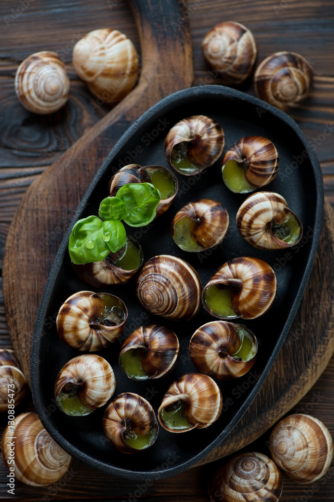 Frying pan with escargot snails on a rustic wooden background Frying pan with escargot snails on a rustic wooden background