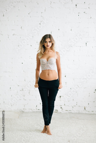 Portrait of beautiful blond woman in bra and black pants
