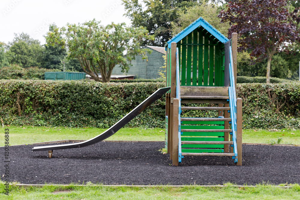 Green wooden house with slider on empty playground Green wooden house with slider on empty playground